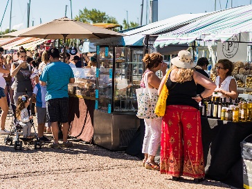 People buying food and items from outdoor market stalls.