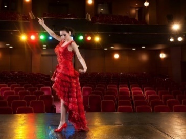 A person performing a cultural dance on a stage in a theater.