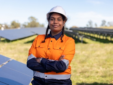 A person working in a field with solar panels.