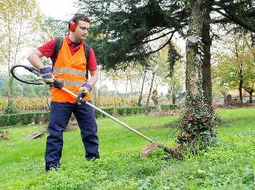 A worker using gardening tools to maintain a public space.